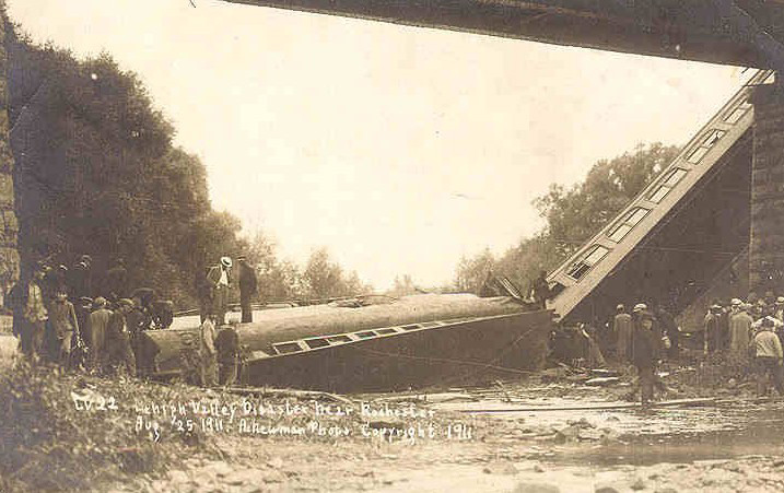 Lehigh Valley coach No. 237, the 10th car in the train, resting on its side in the bed of the Outlet. Lehigh Valley coach No. 293, the 11th car, is standing on one end. [PHOTO: A. Newman, Copyright 1911]