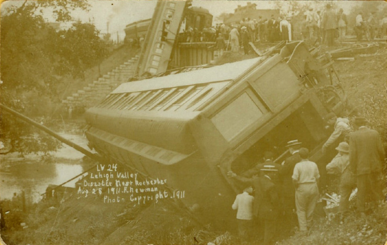 The Pullman sleeping car 'Austin' leaning on its side. In the background the Lehigh Valley coach No. 293 is standing on one end in the bed of the Outlet, and resting against the corner of the parlor car 'Emelyn' on the bridge. [PHOTO: A. Newman, Copyright 1911]